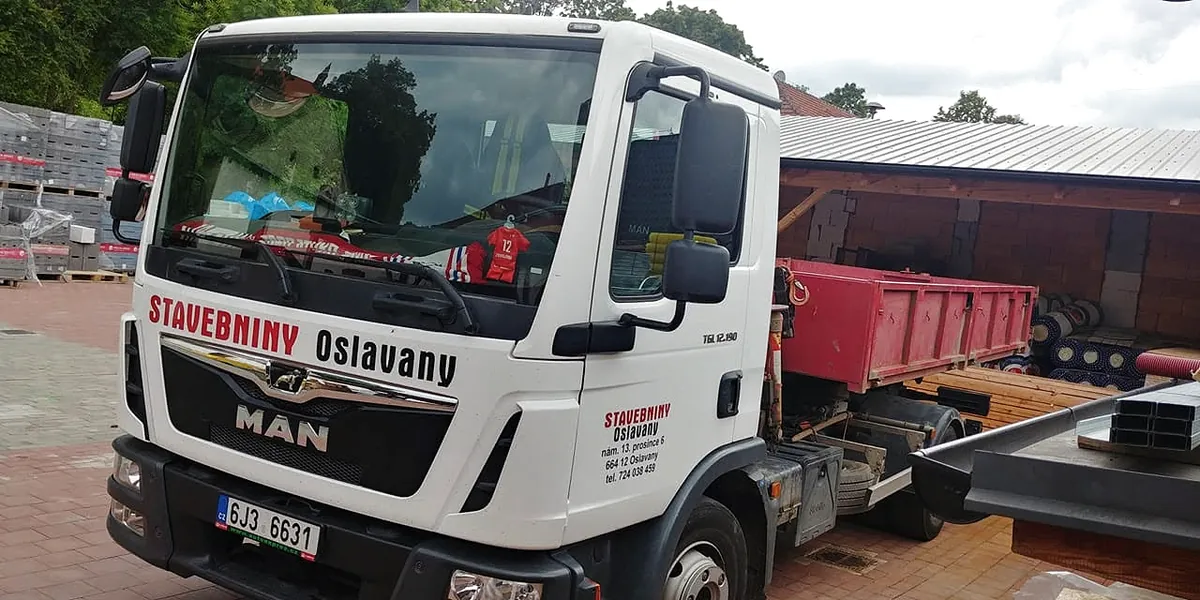 Firemní nákladní auto MAN Stavebnin Oslavany s materiálem připraveným k rozvozu